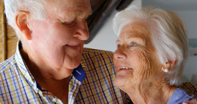 Close-up of old Caucasian senior couple looking at each other in a comfortable home. They are embracing each other 4k