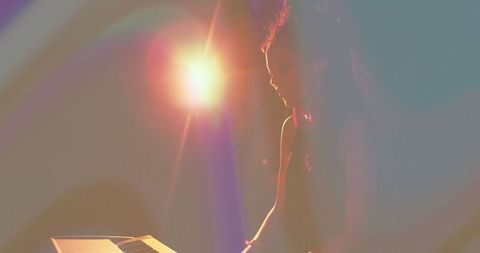 Woman musican playing electronic keyboard with lens flare