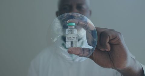 Scientist holding covid-19 vaccine with spinning globe overlay