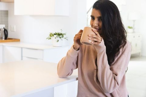 Young Woman Sipping Drink in Minimalist Kitchen Setting Relaxed Atmosphere