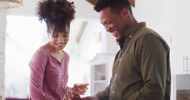 Happy african american couple cooking and drinking wine in kitchen. Spending quality time at home together concept.