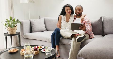 Happy Couple Using Tablet Celebrating Quality Time on Comfortable Sofa