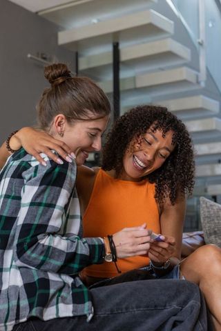 Diverse friends sharing excitement over device in modern living space