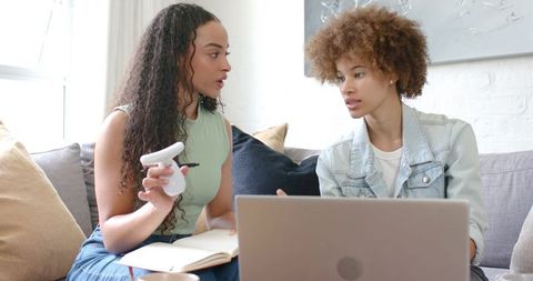 African American Women Collaborating on Laptop and Notes in Sunlit Living Room