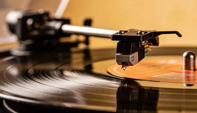 Turntable stylus tracing vinyl grooves on orange label record for vintage music nostalgia