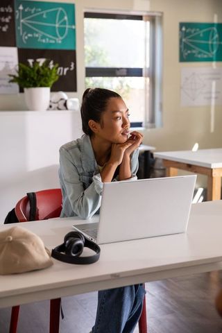 Focused Asian Student Using Laptop in Classroom Setting