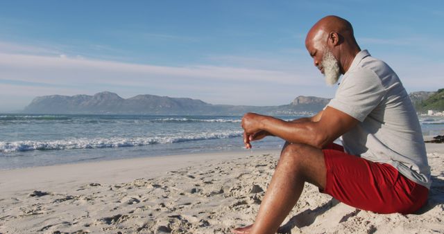 Senior african american man sitting at the beach. healthy outdoor leisure time by the sea.