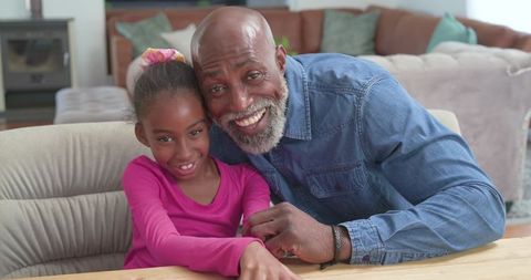 Smiling grandfather and granddaughter sharing warm intergenerational bond at home