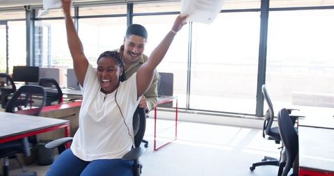 Playful office moment: team celebration with chair racing joy
