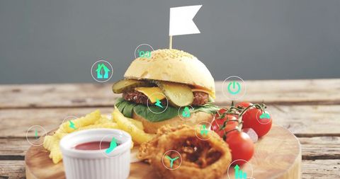 Serving sesame burger with fries and onion rings on wooden board featuring eco icons