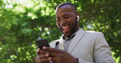 Joyful Man Using Smartphone Outdoors with Earphones
