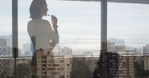 Reflective Businesswoman Overlooks Cityscape from Windowed Office