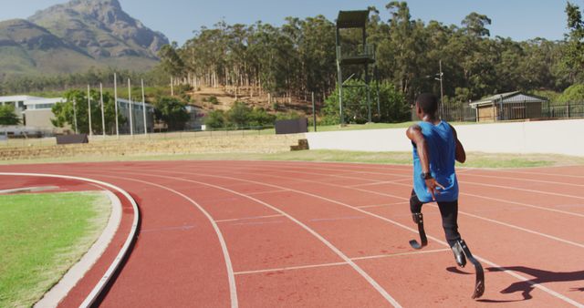 African american male athlete with prosthetic legs training at empty, stadium copy space. Sport, disability, atletics and fitness, unaltered.