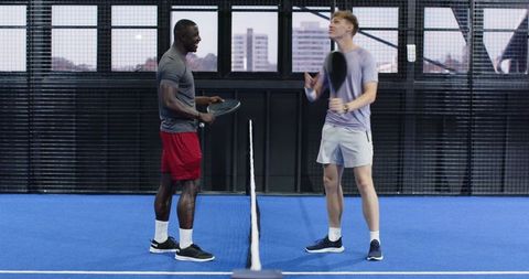 Friends Collaborating on Paddle Court with Joyful Smiles