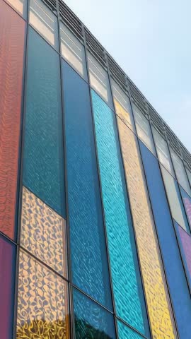 Tilting camera revealing vibrant vertical glass facade with textured multicolor panels
