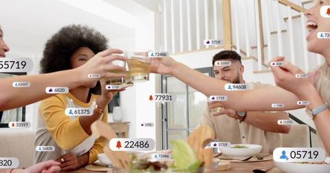 Friends clinking glasses around wooden dining table with social media notifications overlay