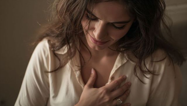 Introspective woman placing hand on chest soft warm closeup conveying gratitude