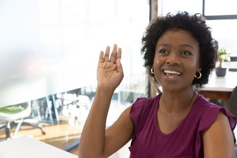 Confident Woman Raising Hand in Modern Office Workspace