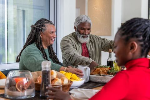 Senior african american couple sharing family meal, passing roasted turkey together