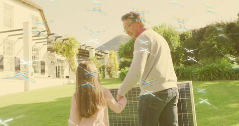 Father walking holding daughter beside solar panel sunny backyard showcasing renewable energy