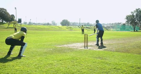 Diverse Team of Cricketers Engaged in Exciting Match on Lush Green Field