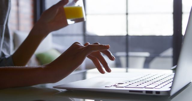 Person Working on Laptop with Glass of Juice in Hand - Download Free Stock Images Pikwizard.com