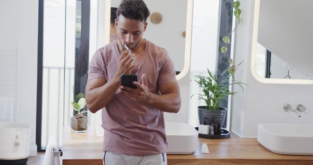 Young Man Brushing Teeth and Using Smartphone in Modern Bathroom - Download Free Stock Images Pikwizard.com