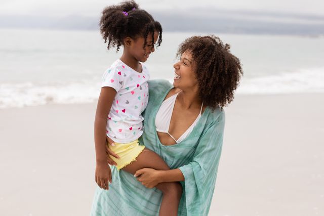 Mother and daughter enjoying a sunny day at the beach, perfect for family, parenting, and vacation themes. Ideal for use in advertisements, blogs, and social media posts about family bonding, summer activities, and outdoor fun.