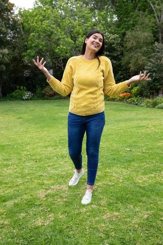 Joyful Woman Shrugging Outside in Casual Attire Enjoying Nature