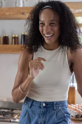 Laughing african american woman stirring eggs wearing headband in bright rustic kitchen