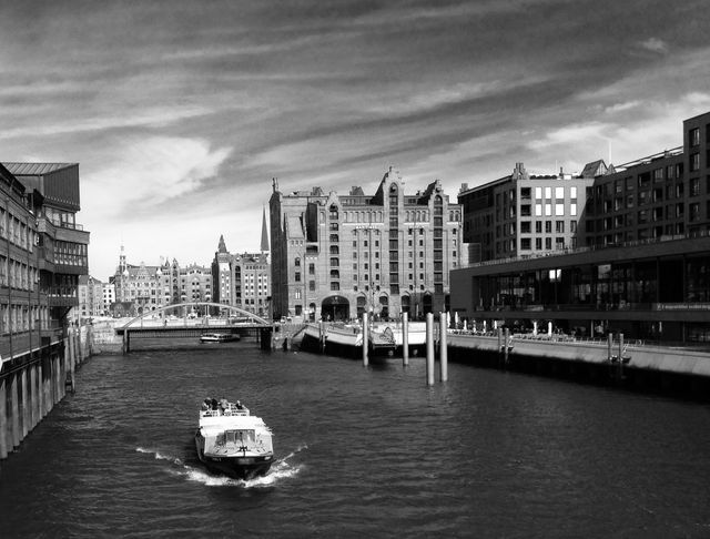 Boats navigating urban waterways with historic architecture in background amidst cloudy sky. Perfect for travel blogs, publications about historic European cities, or any project highlighting urban waterways and architecture.