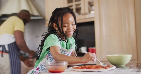 Joyful young girl making pizza with father in bright kitchen