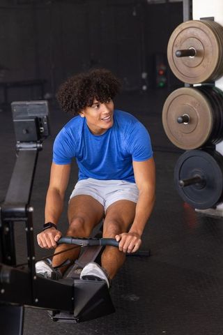 Energetic Man Exercising on Rowing Machine in Gym Environment