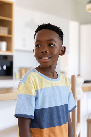 African american boy smiling and looking away in bright modern kitchen