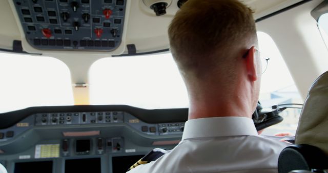Caucasian pilot in the cockpit of an airplane, with copy space. His focus on the flight controls ensures a safe journey for all on board.