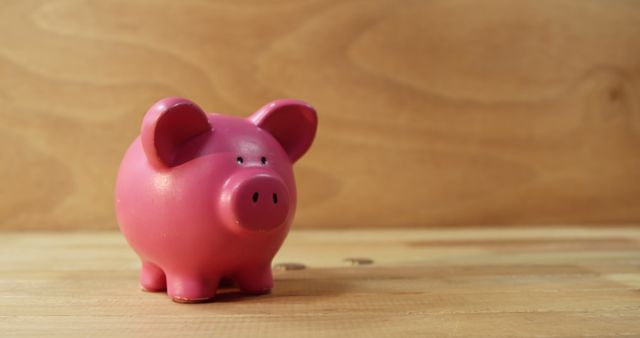 A pink piggy bank stands against a wooden background, symbolizing savings and financial planning, with copy space. Its presence encourages the practice of setting aside funds for future needs or investments.