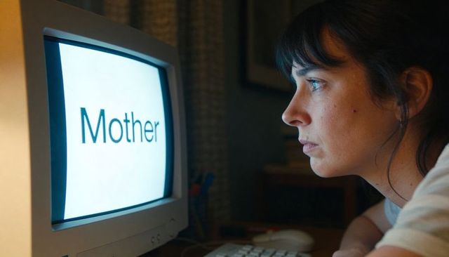 Leaning woman gazing at retro crt monitor displaying 'mother' in moody blue glow