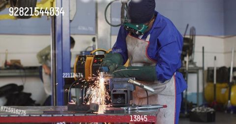 Female metalworker grinding steel with angle grinder, sparks flying in workshop