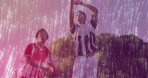Players Raising Arms in Illuminated Field with Light Streaks