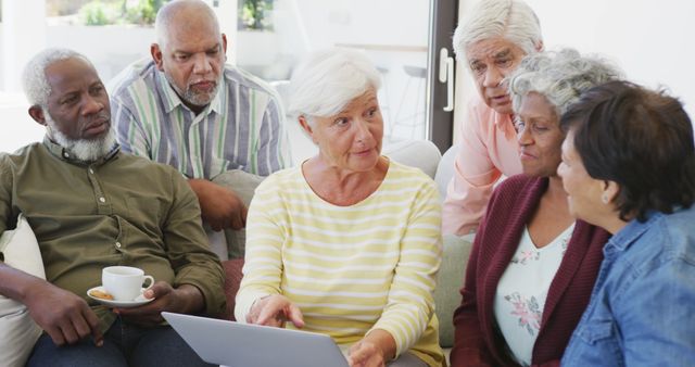 Elderly group discussing content on laptop during casual social gathering. Great for depicting community activities, technology adoption among seniors, retirement life, and social interactions in elderly communities.