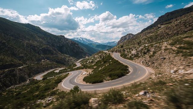 Winding mountain pass road with dramatic hairpin turns and alpine valley scenic views