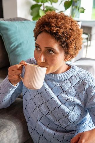 Woman Relaxing in Cozy Living Room with Hot Beverage
