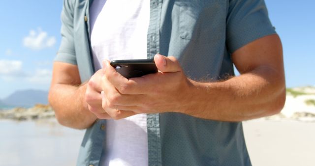 Man in casual attire using smartphone at the beach - Download Free Stock Images Pikwizard.com