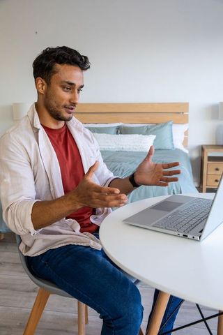 Man Engaging in Online Meeting From Home Office Bedroom Setting