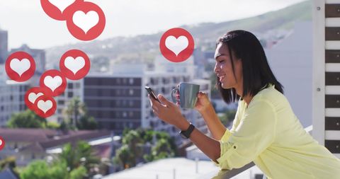 Woman relaxing with smartphone and coffee overlooking city skyline