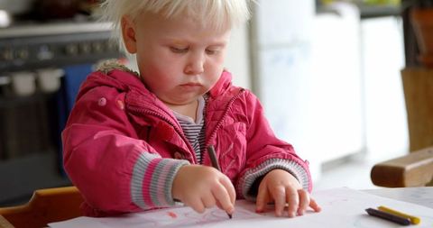 Caucasian toddler drawing with crayons at home