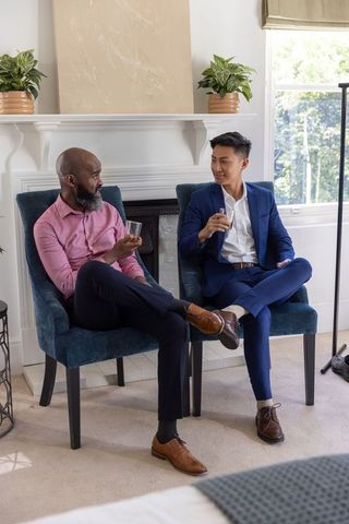 Black and asian colleagues chatting over drinks in professional lounge by fireplace
