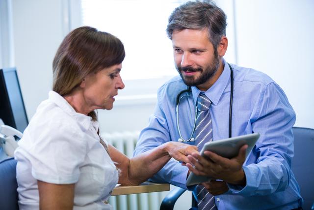 Male doctor consulting with female patient using a digital tablet in a hospital setting. Ideal for use in healthcare, medical technology, patient care, and hospital-related content. Can be used in articles, blogs, and advertisements focusing on modern healthcare practices and doctor-patient interactions.