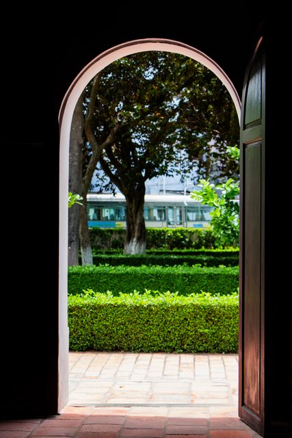 View through an open door reveals a lush garden with dense greenery and trees. Ideal for themes related to peace, nature, and tranquility. Perfect for illustrating concepts of inviting spaces, outdoor relaxation, or natural beauty.