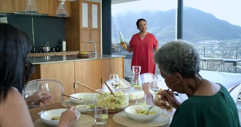 African american women enjoying family lunch in modern kitchen with mountain view terrace